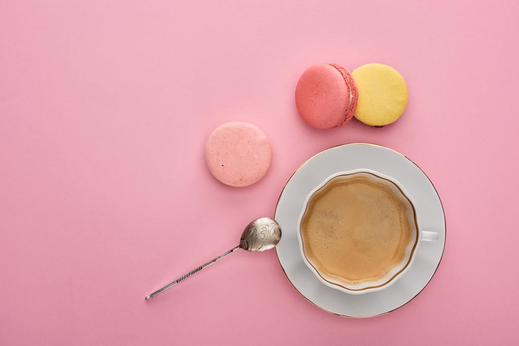 Draufsicht auf köstliche französische Makronen in der Nähe von Kaffee auf rosa Hintergrund mit Kopierfläche - Foto, Bild