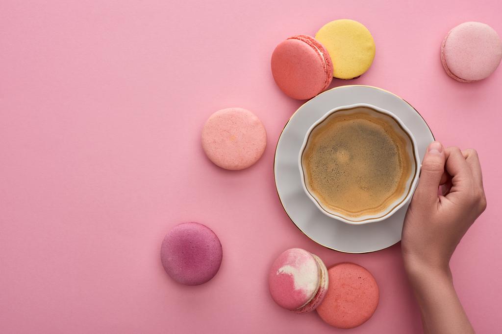 vista recortada de la mujer bebiendo café con deliciosos macarrones franceses sobre fondo rosa
 - Foto, Imagen