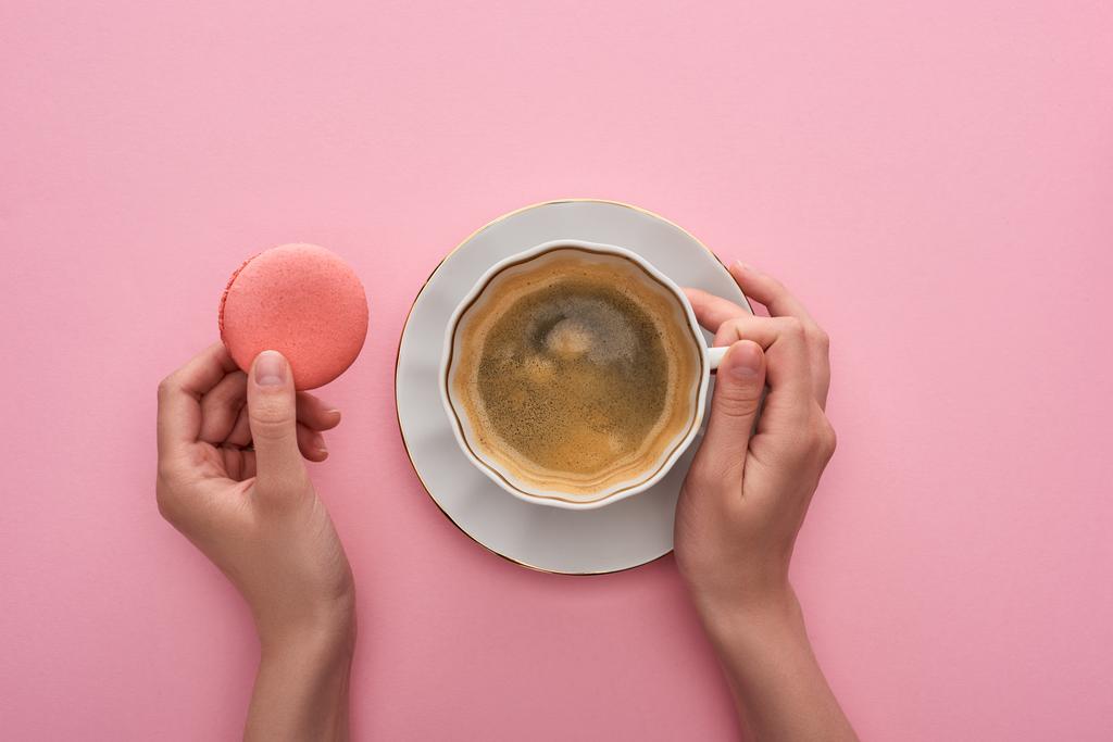 μερική θέα της γυναίκας πίνοντας καφέ με νόστιμο γαλλικό αμυγδαλωτό σε ροζ φόντο - Φωτογραφία, εικόνα