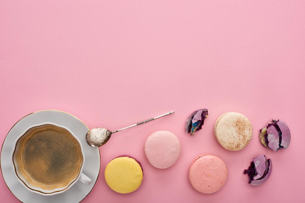 top view of delicious French macaroons near coffee with silver spoon on pink background with copy space - Photo, Image