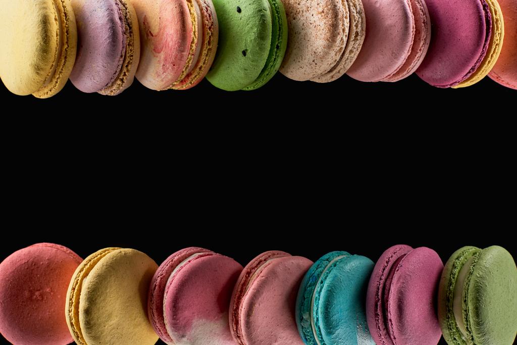 σειρές από νόστιμα πολύχρωμα γαλλικά αμυγδαλωτά διαφορετικών γεύσεων που απομονώνονται σε μαύρο με χώρο αντιγραφής - Φωτογραφία, εικόνα