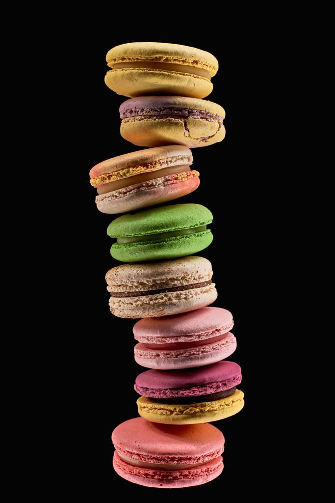 pile de délicieux macarons français frais de différentes saveurs isolés sur noir
 - Photo, image