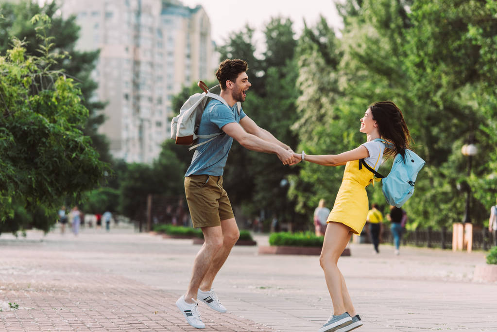 красивый мужчина и азиатская женщина улыбаются, прыгают и держатся за руки
  - Фото, изображение