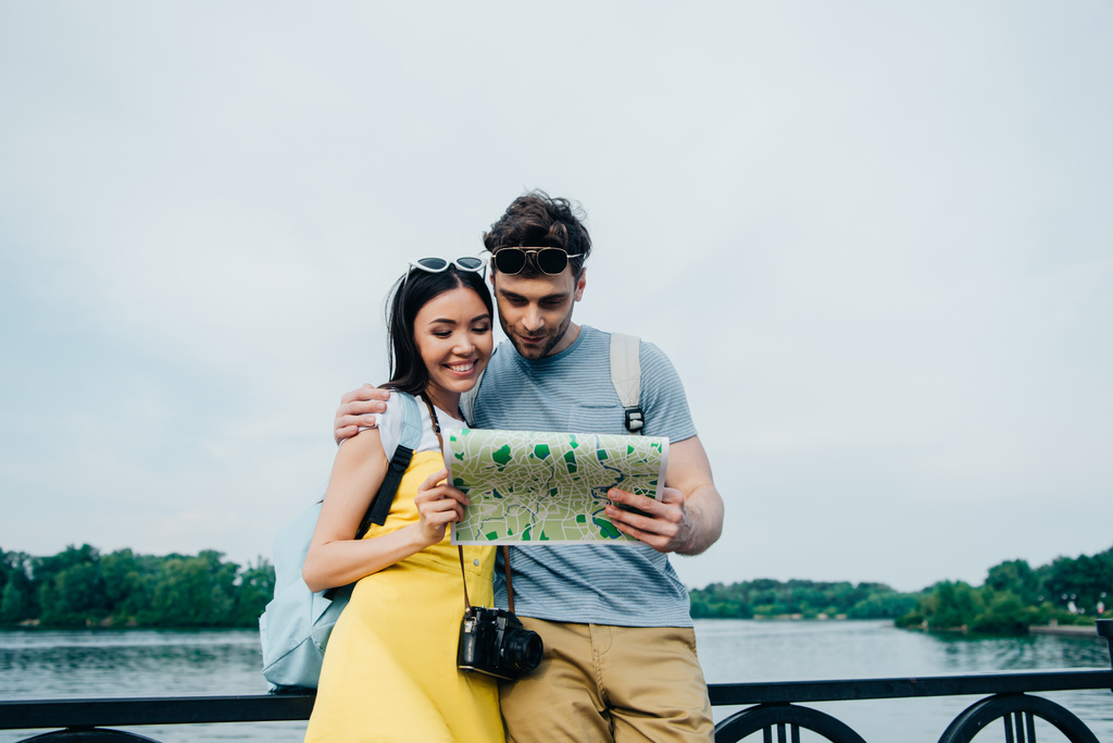 handsome man and asian woman hugging and looking at map  - Photo, Image
