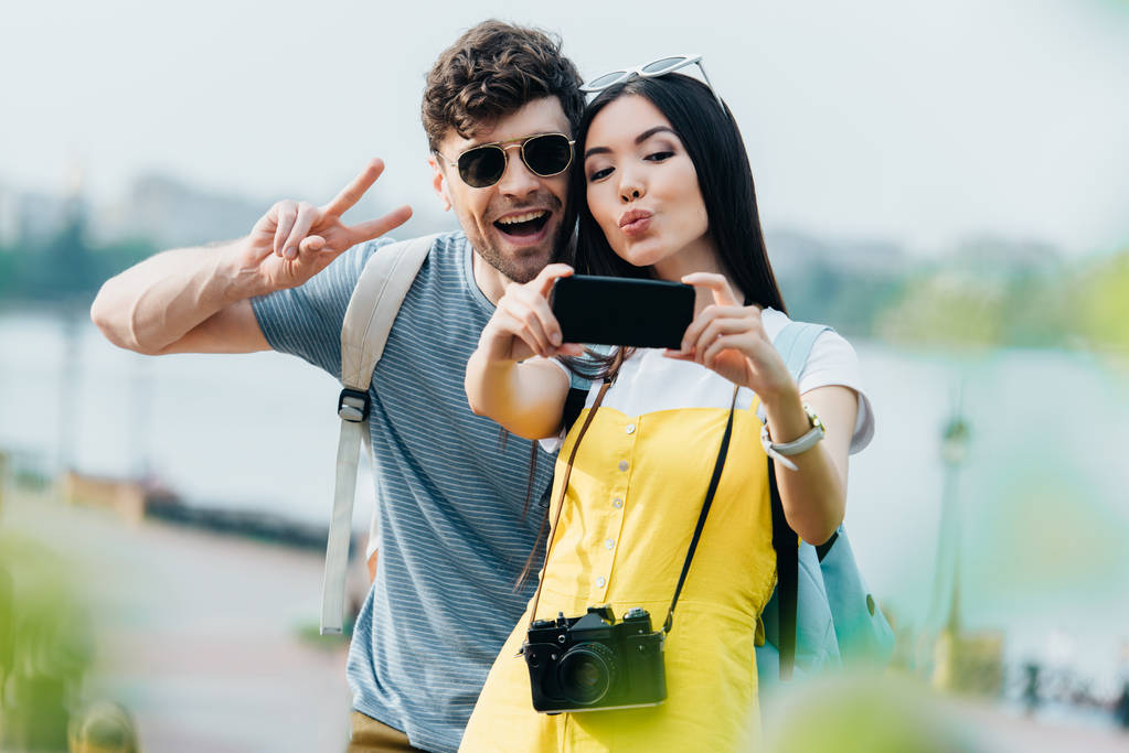 bel homme montrant signe de paix et asiatique femme prendre selfie
  - Photo, image