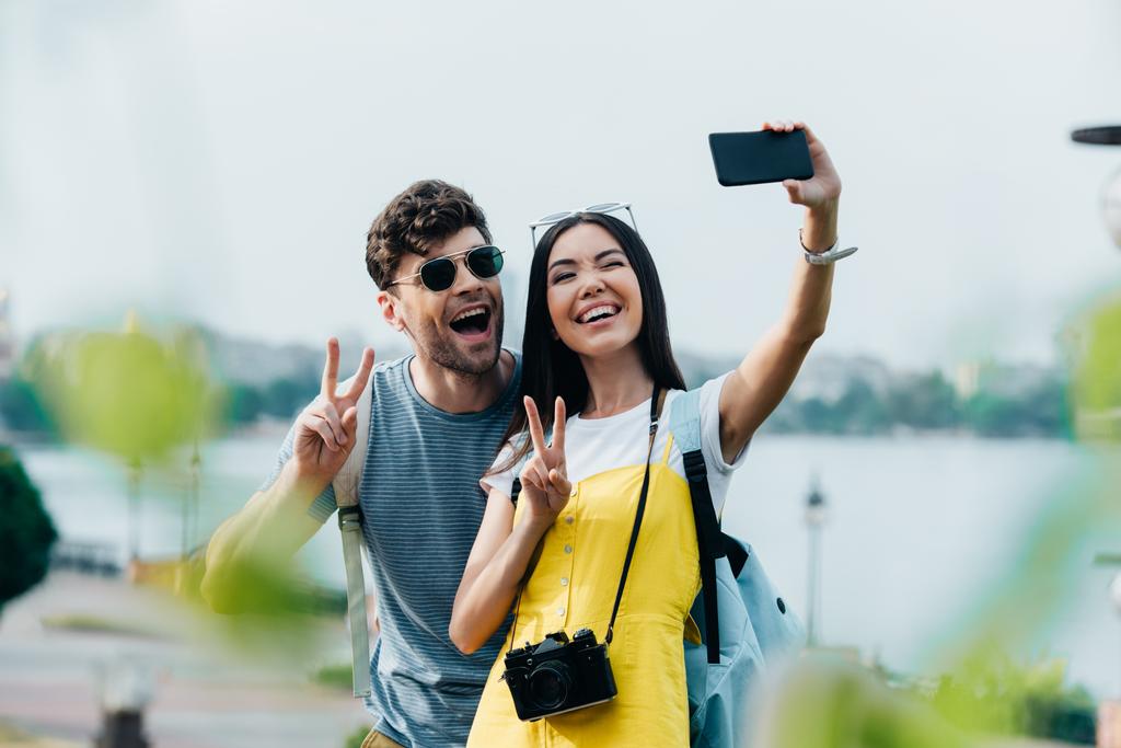 bel homme et femme asiatique montrant des signes de paix et de prendre selfie
  - Photo, image