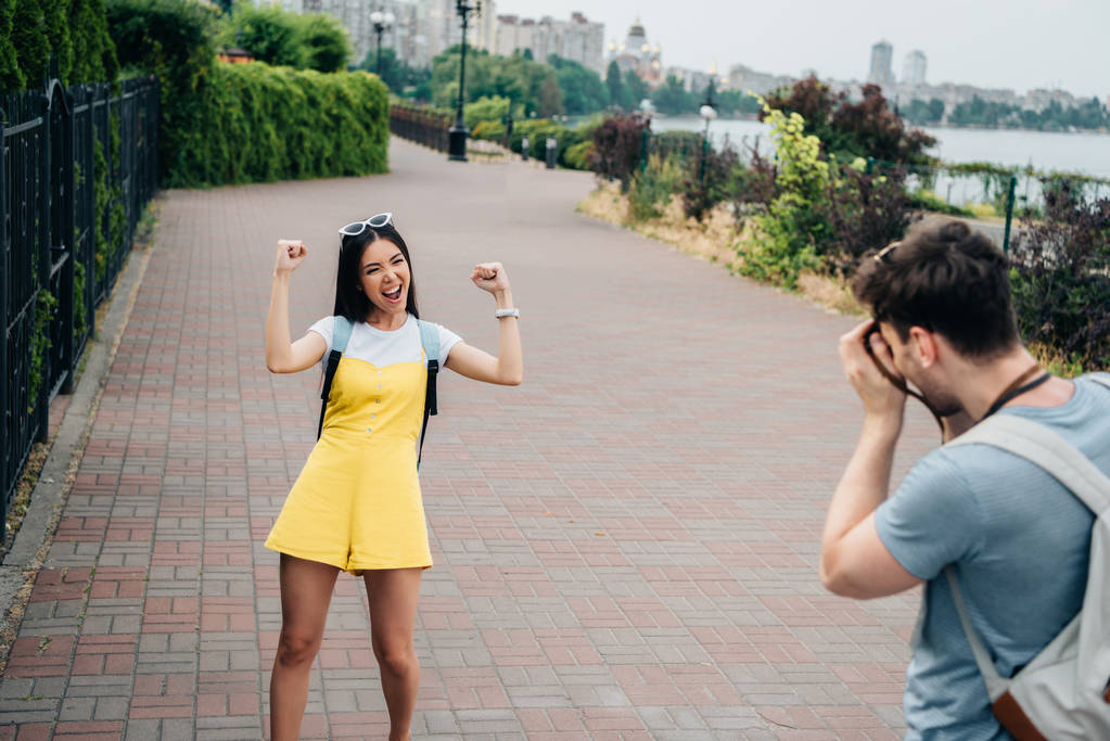 hombre tomando foto y asiático mujer mostrando sí gesto
 - Foto, imagen