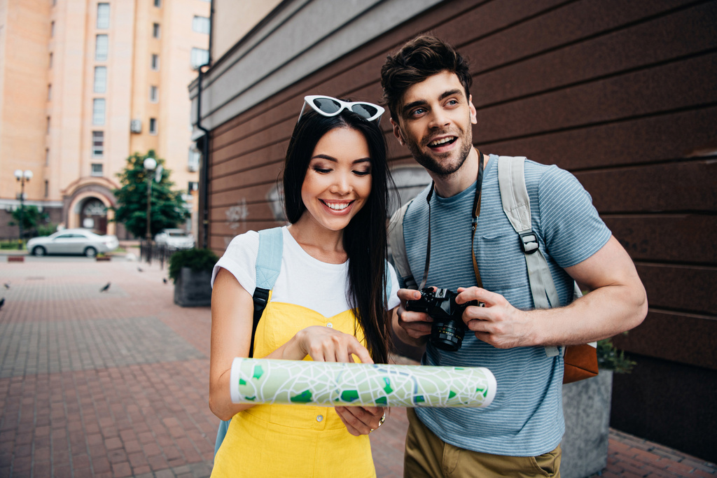  guapo hombre con digital cámara mirando lejos y asiático mujer holding mapa
  - Foto, Imagen