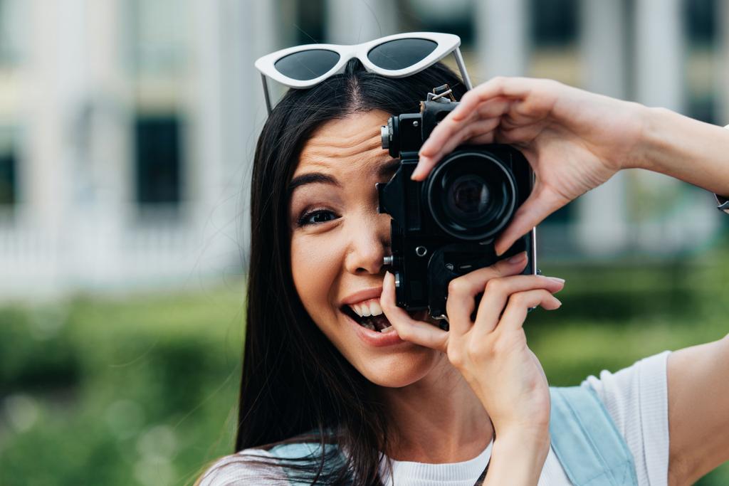 Atrakcyjna i Azjatycka kobieta z okularami uśmiechniętymi i robienia zdjęć  - Zdjęcie, obraz
