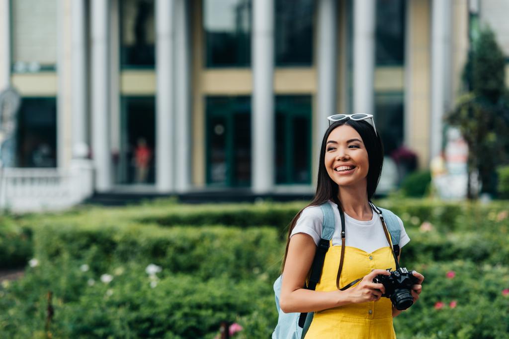  attrayant et asiatique femme avec appareil photo numérique regardant loin
 - Photo, image