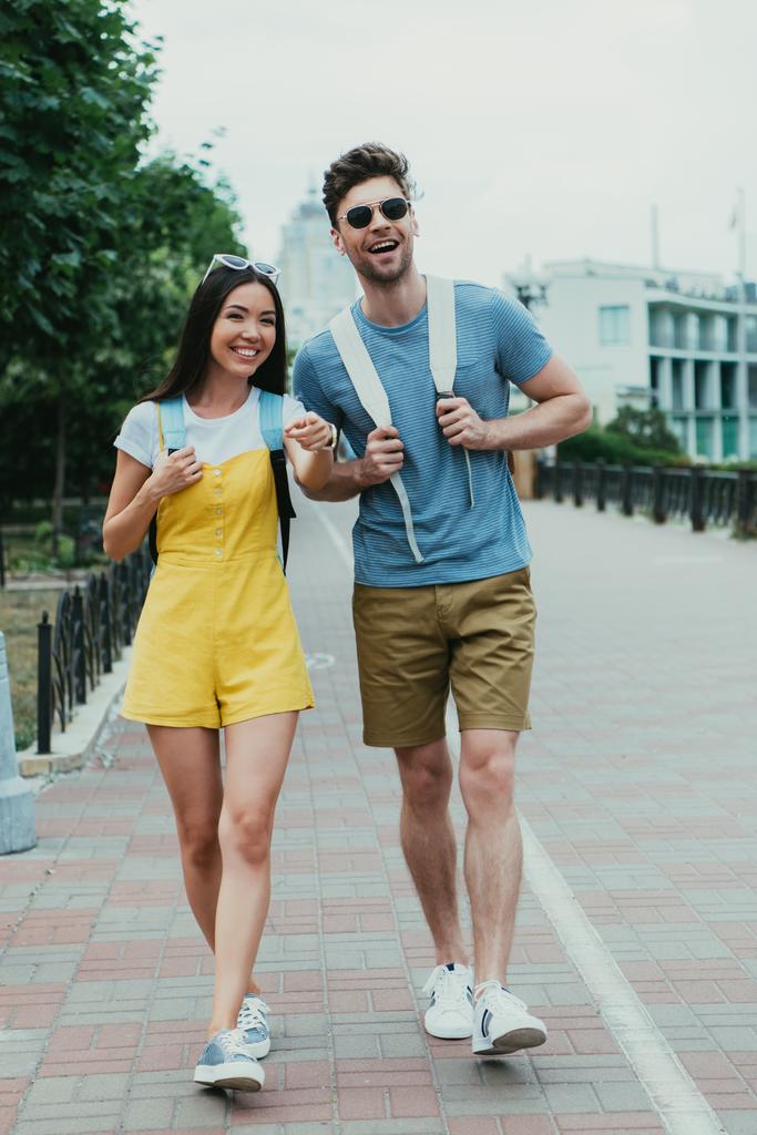 knappe man en Aziatische vrouw wandelen en wegkijken  - Foto, afbeelding
