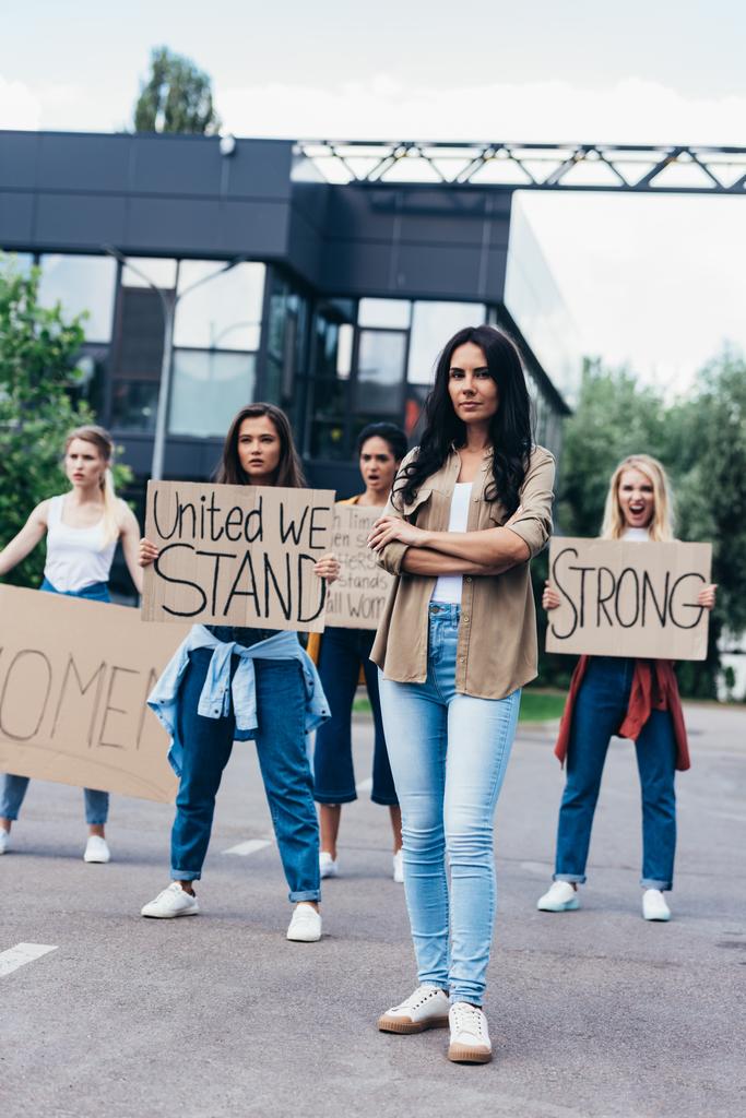 sokakta sloganlar atan feministlerin yanında duran kadının tam boy görünümü - Fotoğraf, Görsel