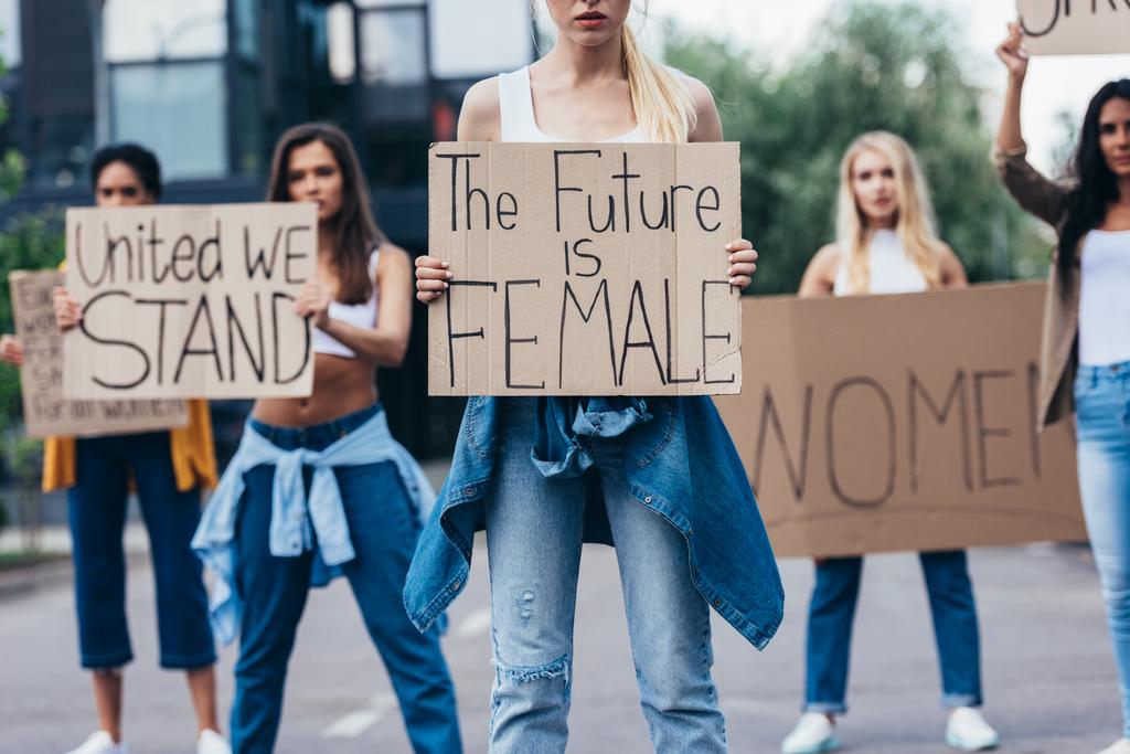 vista cortada da mulher segurando cartaz com inscrição o futuro é feminino perto feministas na rua
 - Foto, Imagem