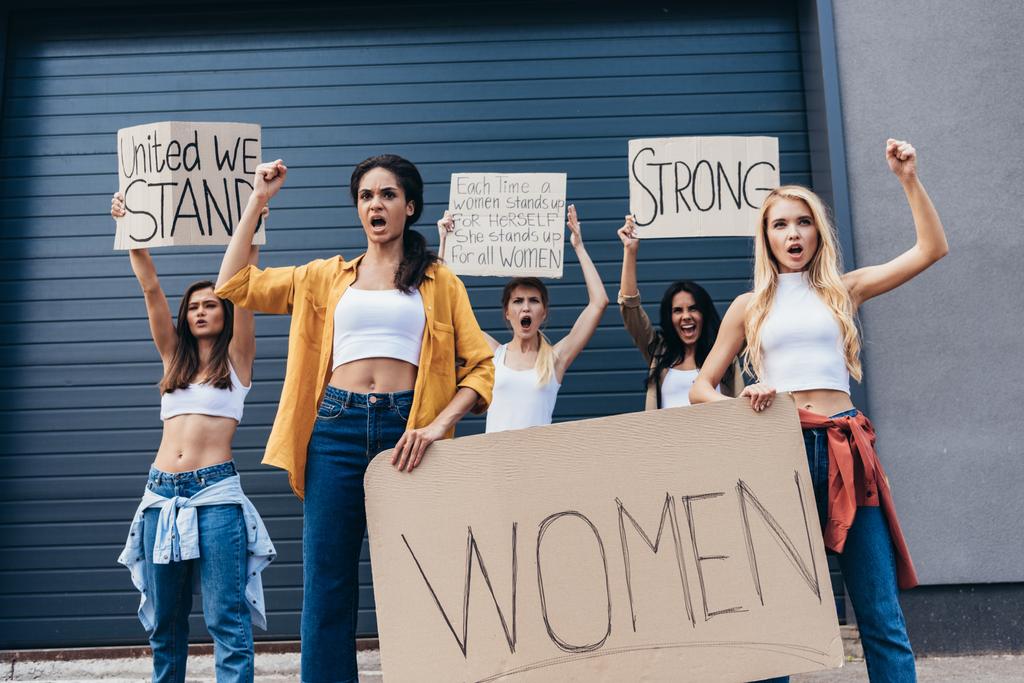 пять феминисток с плакатами с лозунгами и криками на улице
 - Фото, изображение