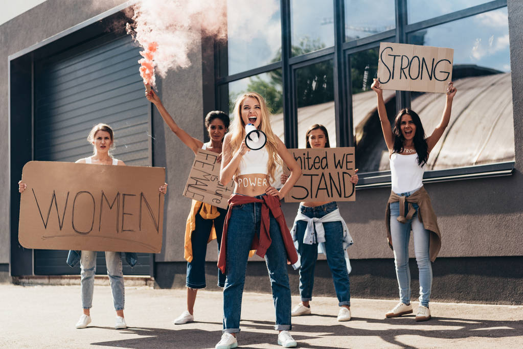 vue complète de crier féministes multiethniques avec haut-parleur tenant des pancartes avec des slogans dans la rue
 - Photo, image