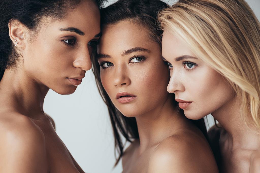 tre attraenti giovani donne multietniche distolgono lo sguardo isolate sul grigio
 - Foto, immagini