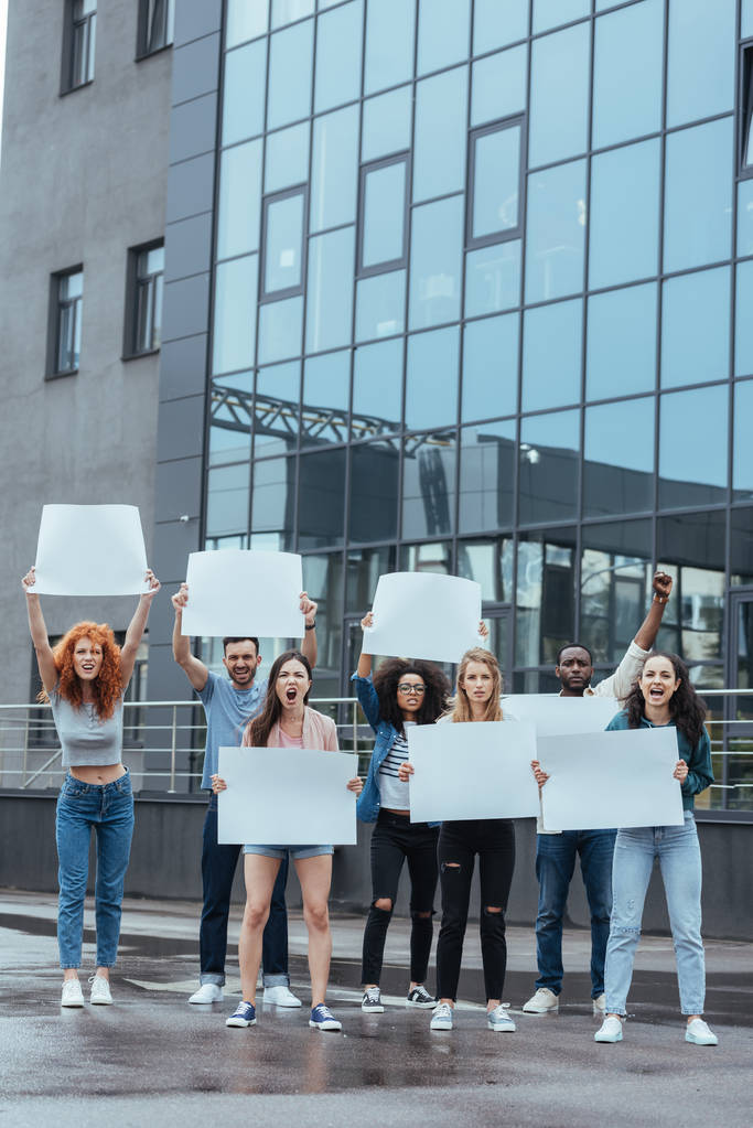 grupo multicultural emocional de pessoas com cartazes em branco perto do edifício
  - Foto, Imagem