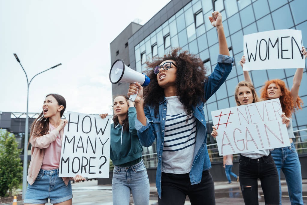selectieve focus van Afro-Amerikaanse meisje gebaren terwijl het houden megafoon in de buurt van meisjes op vergadering  - Foto, afbeelding