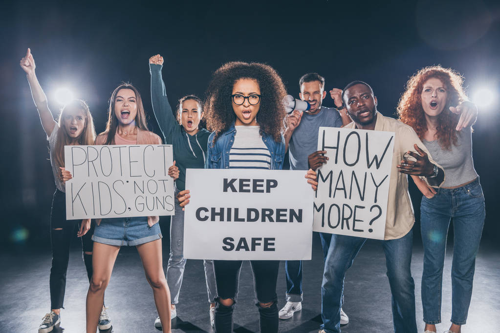 emocjonalna African American kobieta trzyma afisz z Keep dzieci bezpieczne napis w pobliżu grupy ludzi na czarnym  - Zdjęcie, obraz
