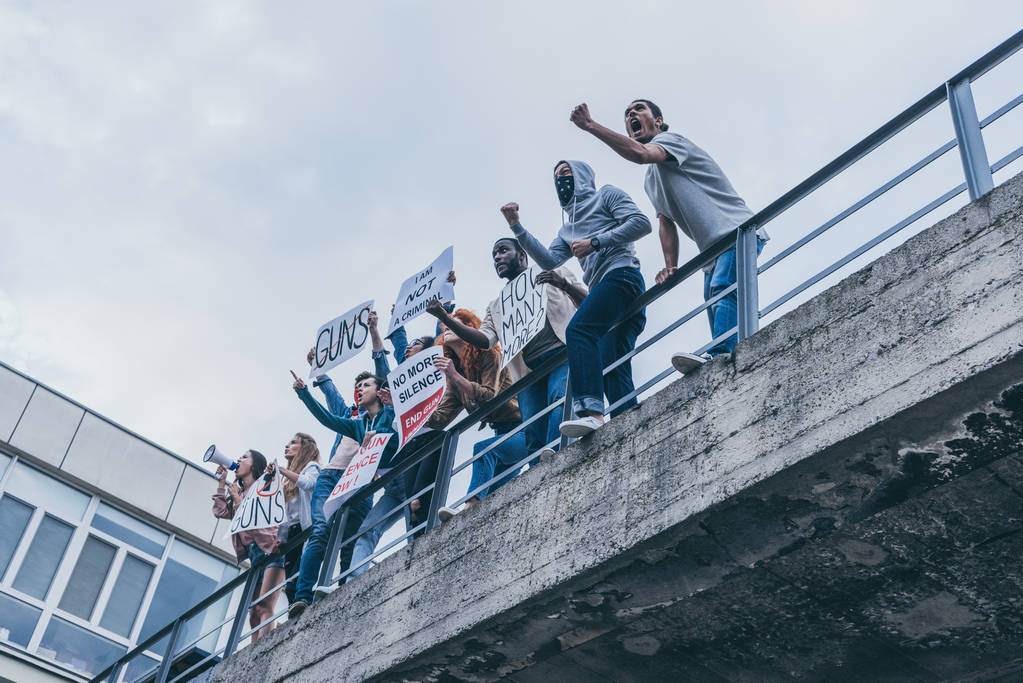 vista de ángulo bajo de personas multiculturales gritando y haciendo gestos mientras sostiene pancartas
  - Foto, imagen