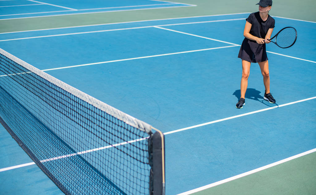 Jovem desportista a jogar ténis no campo de ténis azul
 - Foto, Imagem