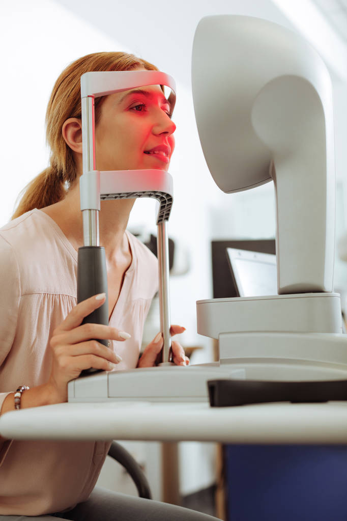 Tmavovlasá žena se usmívá při návštěvě oftalmologa - Fotografie, Obrázek