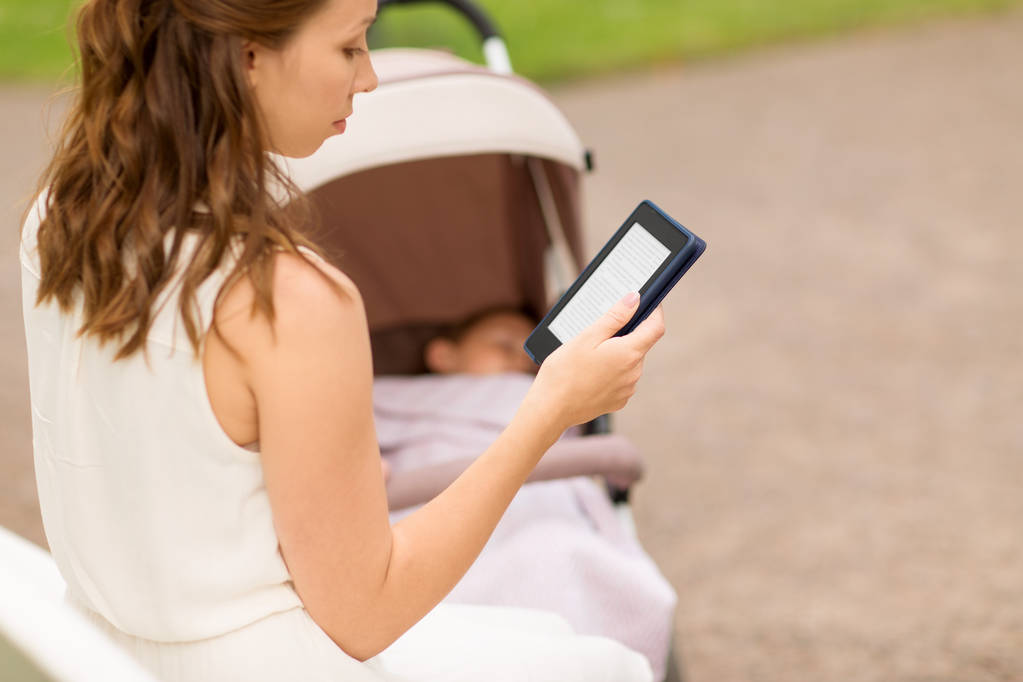 Mutter mit Kinderwagen liest Internet-Buch im Park - Foto, Bild