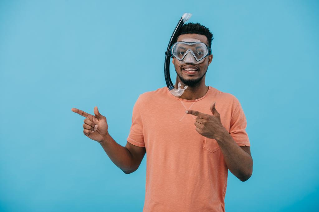 homem afro-americano positivo em máscara de mergulho apontando com os dedos isolados em azul
  - Foto, Imagem