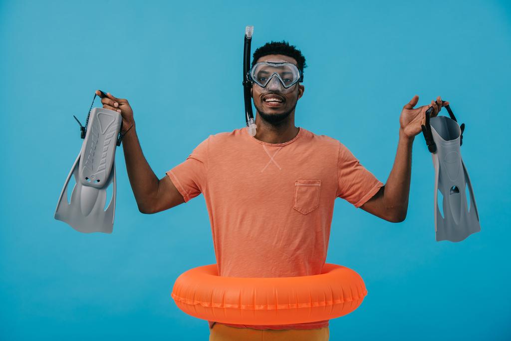 happy african american man in diving mask holding flippers and standing on blue  - Photo, Image