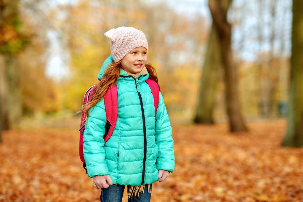 χαρούμενη μαθήτρια με σχολική τσάντα στο πάρκο του φθινοπώρου - Φωτογραφία, εικόνα