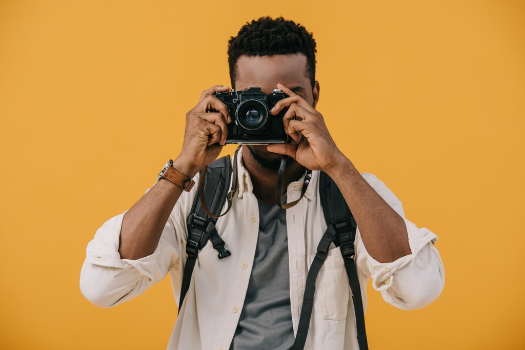 kręcone African American fotograf obejmujące twarz z aparatem cyfrowym na białym tle na pomarańczowo  - Zdjęcie, obraz