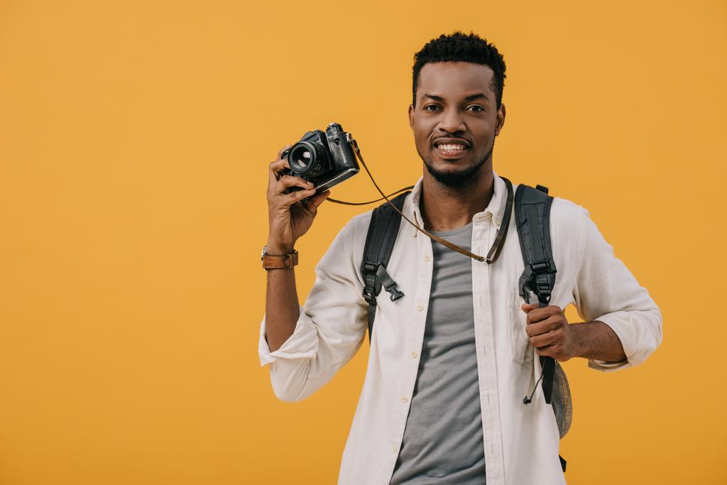 ευτυχισμένος Αφρικανός Αμερικανός άνθρωπος κρατώντας ψηφιακή κάμερα απομονωμένη σε πορτοκαλί - Φωτογραφία, εικόνα