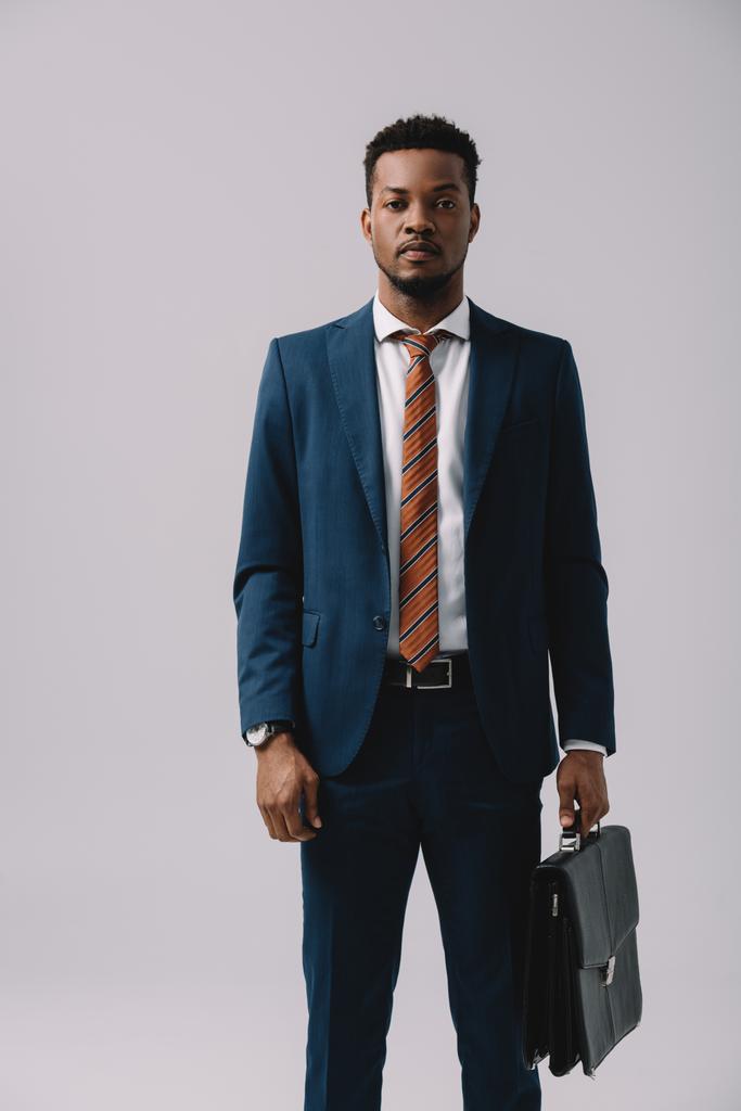 onnistunut afrikkalainen amerikkalainen mies seisoo salkku eristetty harmaa
  - Valokuva, kuva