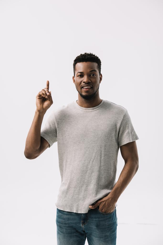 bell'uomo afroamericano puntato con il dito mentre in piedi con la mano in tasca isolato su bianco
  - Foto, immagini