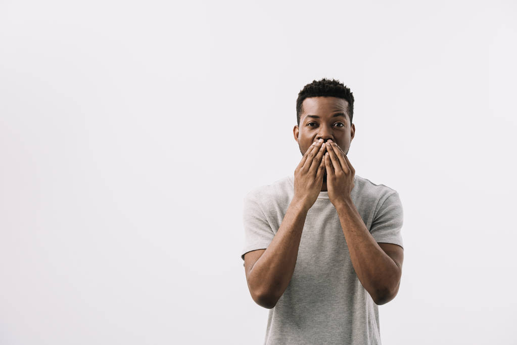 Afroameričan, který zakrýval ústa a hleděl na kameru izolovanou na bílém   - Fotografie, Obrázek