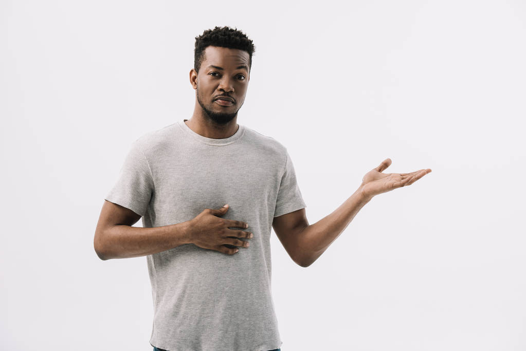 lockiger junger afrikanisch-amerikanischer Mann gestikuliert, während er isoliert auf weiß in die Kamera schaut  - Foto, Bild