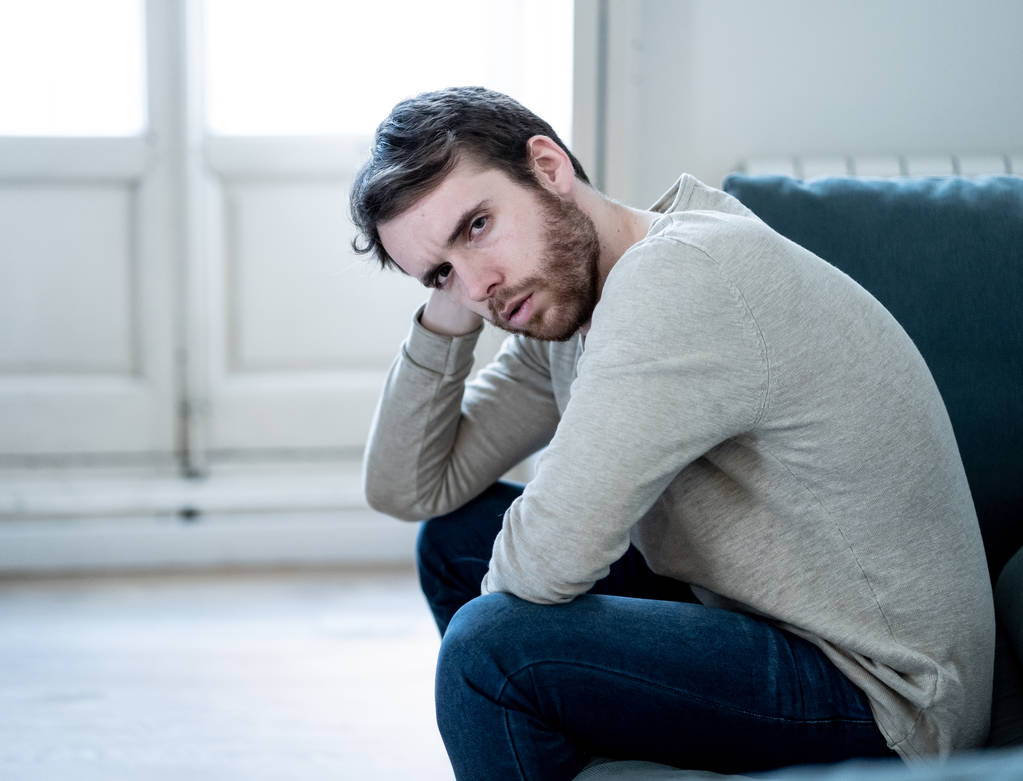 Δυστυχισμένη κατάθλιψη Καυκάσιος άντρας που κάθεται και κείτεται στον καναπέ του σαλονιού νιώθοντας απελπισμένη μια μοναχική δυστυχία από την κατάθλιψη. Στρεσαρισμένος από την εργασία, το άγχος, την καρδιά και τους άνδρες έννοια υγειονομική περίθαλψη. - Φωτογραφία, εικόνα