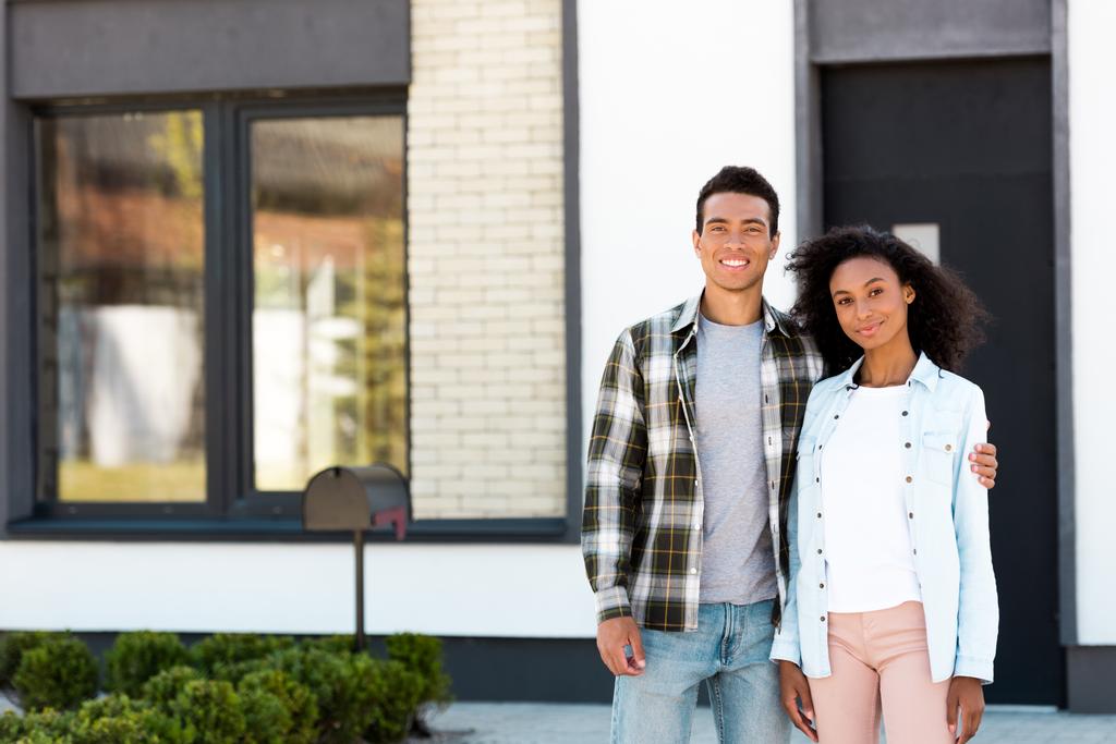 Африканский американский муж и жена стоят рядом с новым домом и смотрят в камеру
  - Фото, изображение
