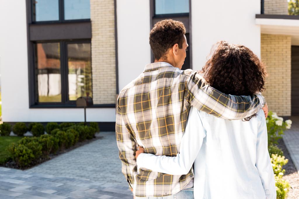 z tyłu widok z African amerykański mężczyzna przytulanie żona podczas chodzenie do dom - Zdjęcie, obraz