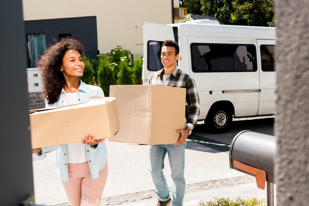 messa a fuoco selettiva della coppia afro-americana che tiene scatole mentre cammina in casa
  - Foto, immagini