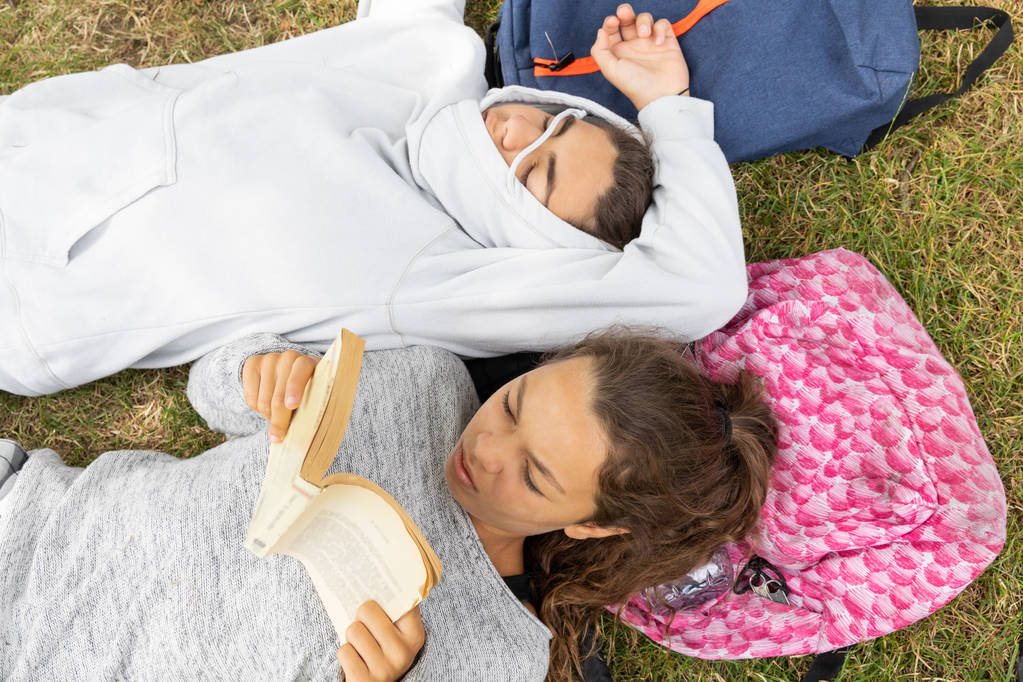 Ragazza legge un libro e ragazzo dorme al parco
. - Foto, immagini