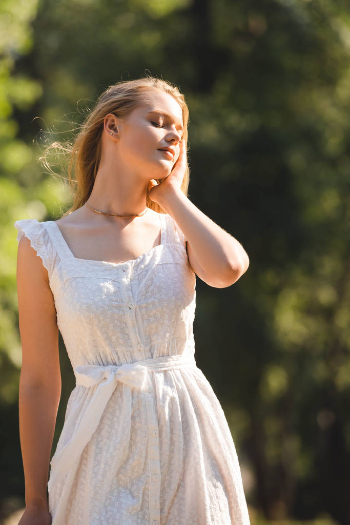 menina bonita em vestido branco de pé no prado com olhos fechados
 - Foto, Imagem