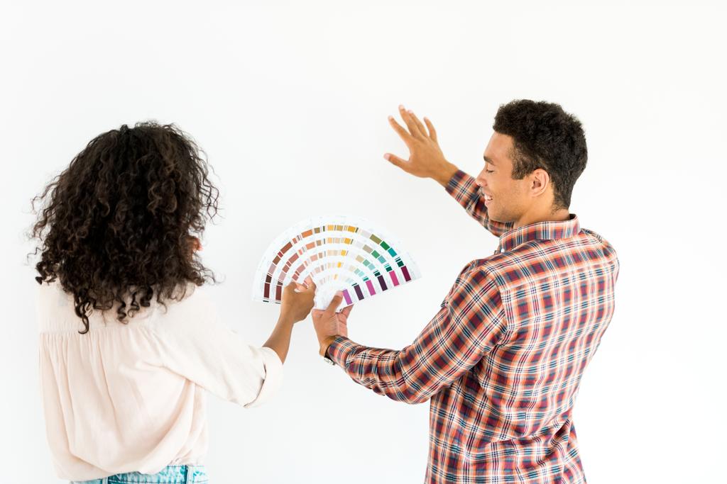 アフリカ系アメリカ人の夫と妻は、白に隔離されたカラフルなパレットから自分の壁の色を選択しようとしています - 写真・画像