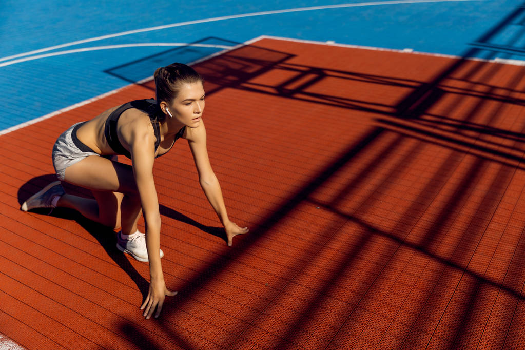 Bir stadyumda hızlı başlangıç konumuna sarışın sportif kadın Runner. - Fotoğraf, Görsel
