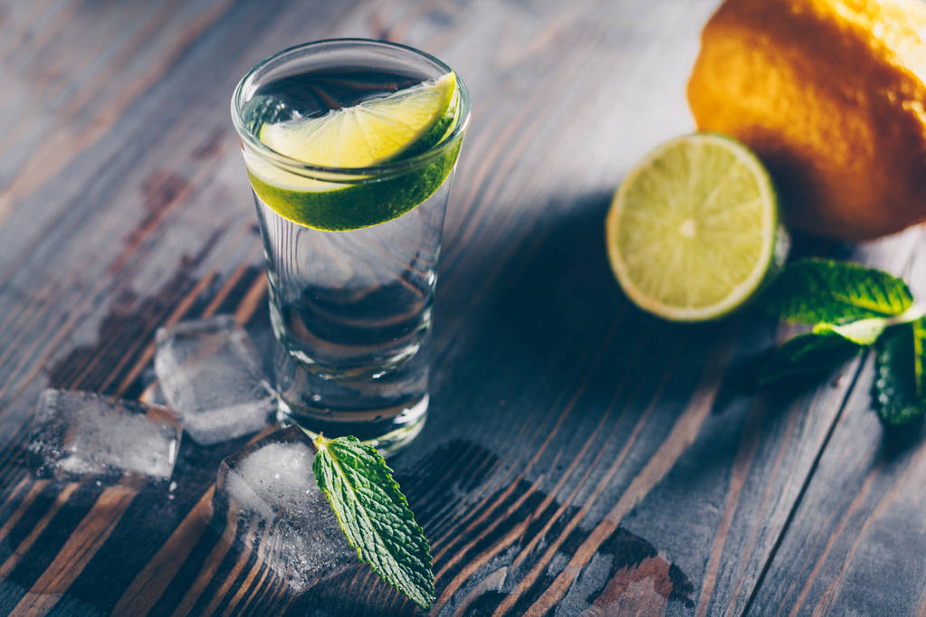 Studené sklo vodky na stole obklopené citrusem, barem - Fotografie, Obrázek