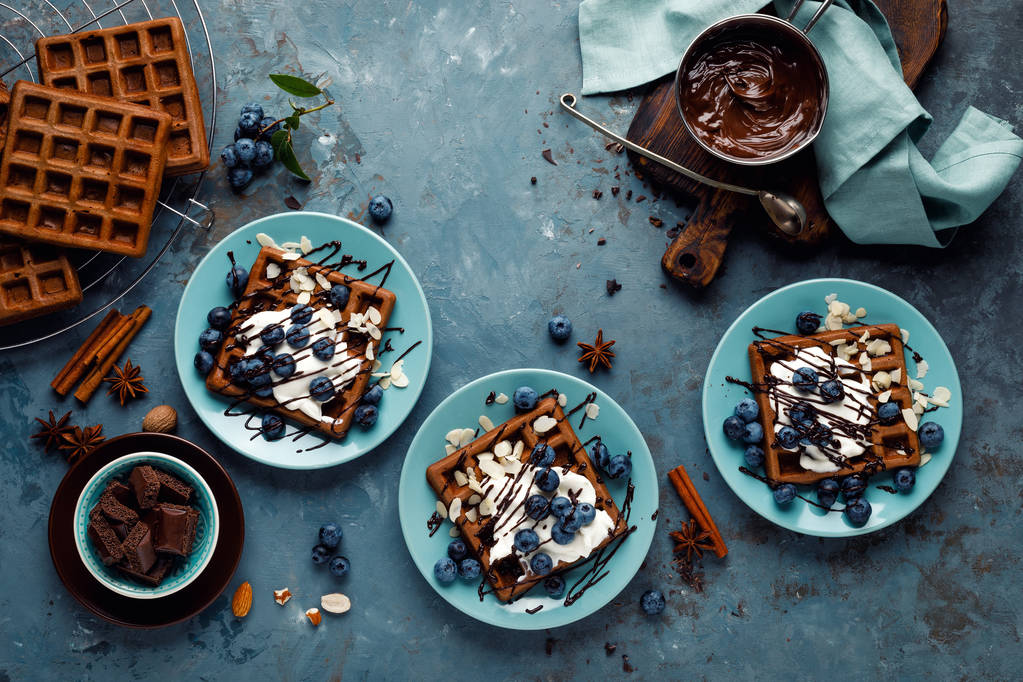 Gaufres belges au chocolat avec crème glacée et bleuets frais sur fond bleu, vue de dessus
 - Photo, image