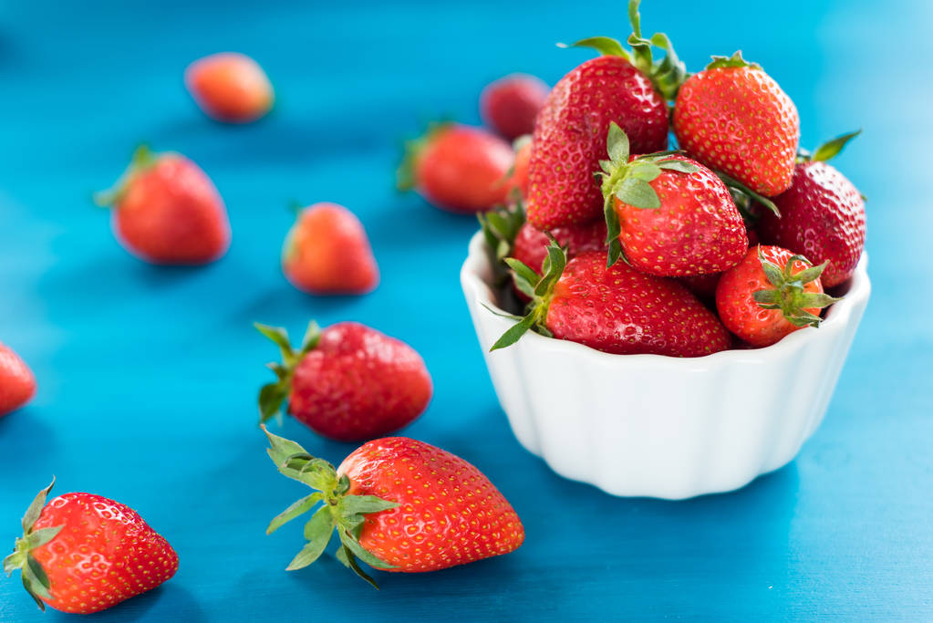 frische helle Erdbeeren in einer Schüssel Draufsicht auf blauem Hintergrund - Foto, Bild