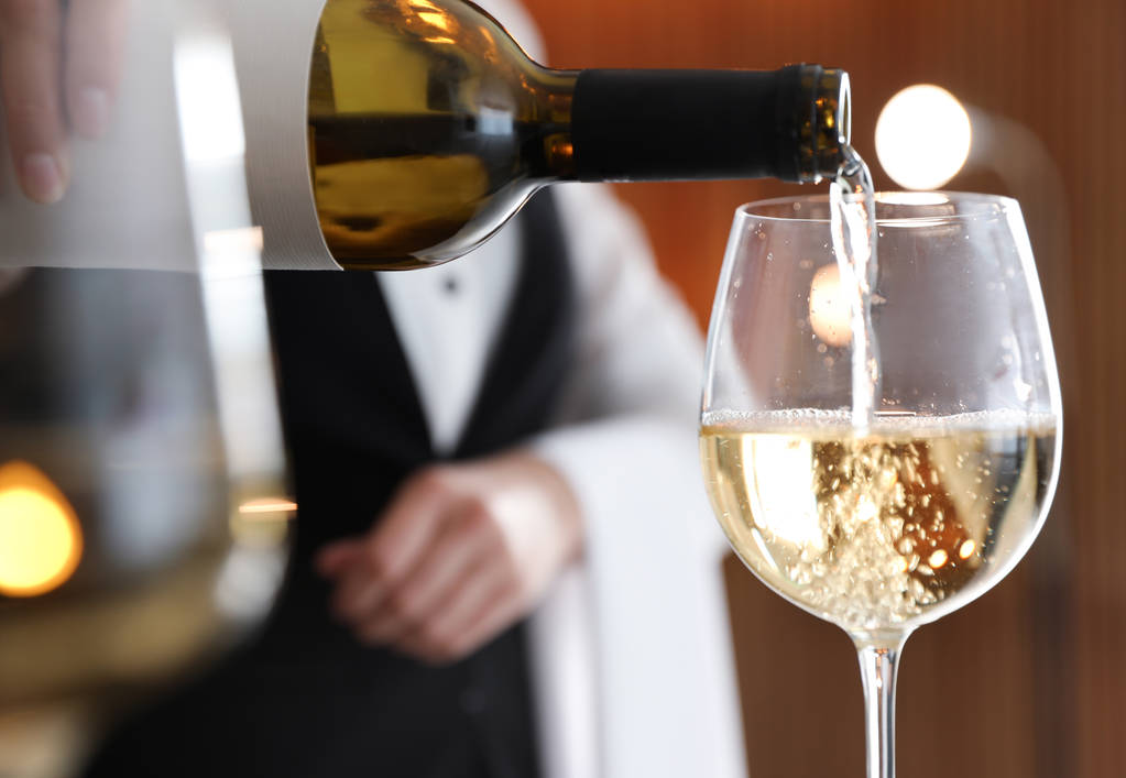 Офіціантка поливає вино в склянку в ресторані, крупним планом
 - Фото, зображення
