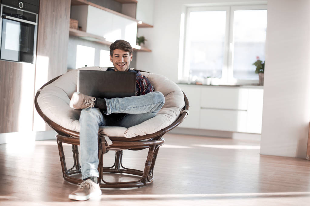 jonge man maakt gebruik van een laptop in zijn moderne appartement. - Foto, afbeelding