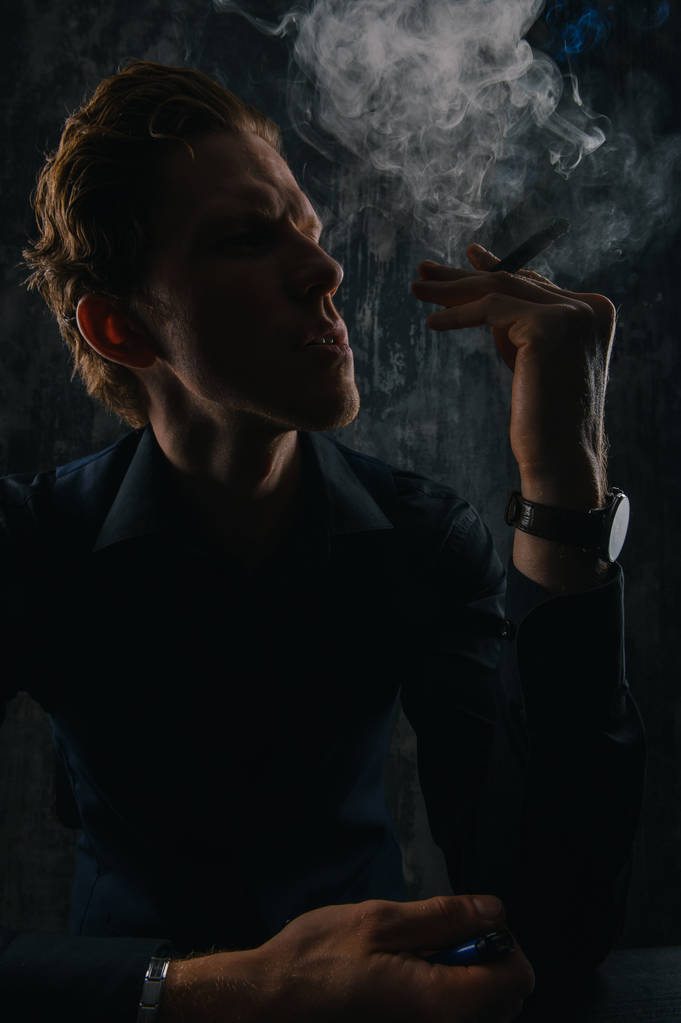 Жестокий таинственный человек с сигарой и дымом изолированы на черном фоне
 - Фото, изображение